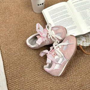 A detailed macro view of pink girls' breathable mesh trainers featuring cute bow-tie laces