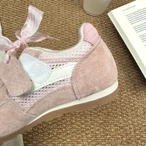 Close-up of pink girls' bow-tie mesh breathable sports sneakers on a cozy brown rug.