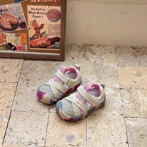 Detailed view of pink and beige children's closed-toe breathable sports sandals on floor.