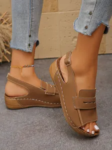 Dettaglio laterale di sandali con zeppa marrone chiaro da donna con design peep toe.