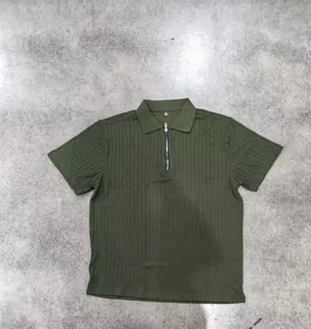 Close-up of olive green men's short-sleeve polo shirt with zip neck and texture.