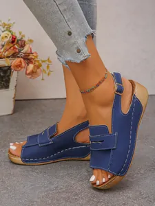 Dettaglio di sandali con zeppa blu con cuciture bianche e suola effetto legno