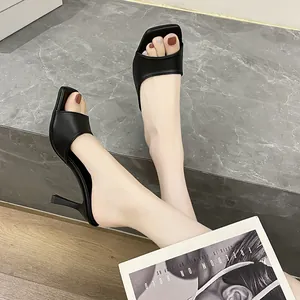 Elegant black square-toe stiletto mules shown from side profile on a grey ledge.