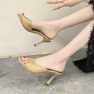 Side view of elegant beige square toe stiletto high heel mules worn by a fashion model
