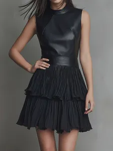 Vue détaillée d'une robe noire sans manches en patchwork de cuir PU avec une jupe plissée à étages