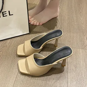 Detail shot of French square-toe stiletto mule sandals in beige on wooden floor.