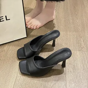 Close-up of elegant black square-toe high-heel mules on wooden floor background