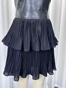Détail d'une robe sans manches en similicuir avec jupon à volants plissés noirs.