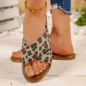 Close-up of leopard print criss-cross straps on flat sandals with gold stud details.