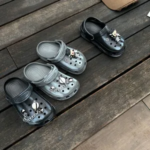 Detailopname van hippe kinderklompen met astronautenbedeltjes in zwart en grijs