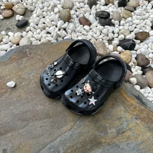 Detailweergave van zwarte kinderklompen met schattige astronaut- en sterbedeltjes