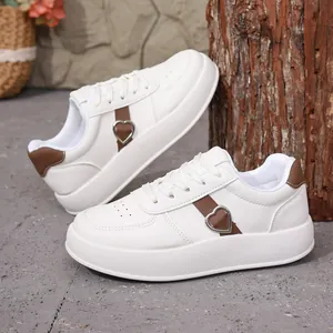 Primer plano de zapatillas blancas de plataforma con hebilla de corazón y correa marrón.