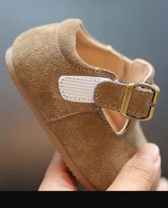 Gros plan détaillé d'une chaussure enfant en daim marron avec boucle et semelle souple.