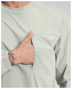 Dettaglio della tasca funzionale verticale con zip sul petto di una maglia sportiva grigia da uomo