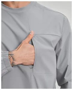 Dettaglio della funzionale tasca pettorale con cerniera su maglia sportiva outdoor grigia.