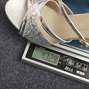 Medición del peso de una elegante sandalia plateada con pedrería que pesa 432,9 g