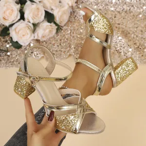 Primer plano de sandalias doradas con purpurina, tacón bloque y elegantes tiras al tobillo.