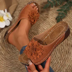 Primer plano de sandalias de cuña marrones para mujer con detalle de flor en 3D