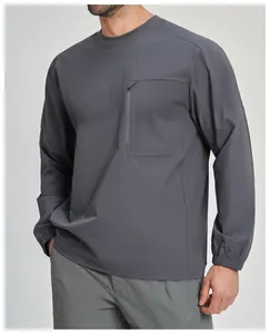 Dettaglio di un top outdoor grigio a maniche lunghe da uomo con tasca sul petto con zip.