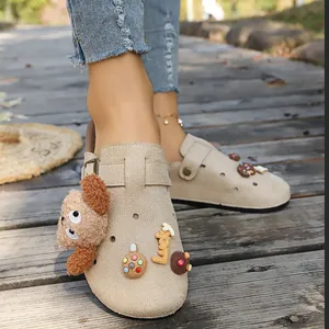 Dettaglio di sabot platform in camoscio beige con ciondoli orsetto e lucky