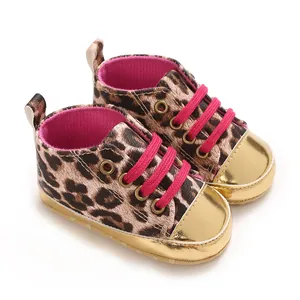 Close-up of leopard print baby shoes with shiny gold toe caps and hot pink laces