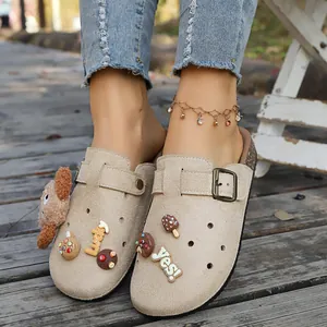 Primo piano di sabot beige con simpatici ciondoli a cartoni animati e fibbia