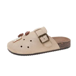 Dettaglio dei sabot in camoscio beige stile Birkenstock con simpatici ciondoli a cartone animato