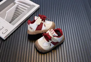 Dettaglio ravvicinato scarpe primi passi traspiranti rosso e beige su trama scura
