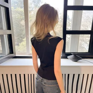 Back view of a black sleeveless vest with delicate lace trim at the neck line.