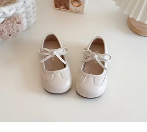 Close-up of cream girls' Mary Janes with decorative bow and soft sole detail