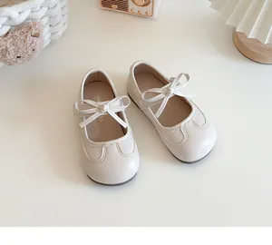 Top view of cute cream baby girls' Mary Jane shoes with bowknot detail on desk.
