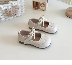 Detailed view of cream girl's Mary Jane shoes with soft soles and bow ties