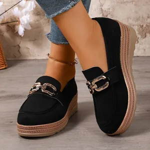 Nahaufnahme schwarzer Damen-Loafer mit goldener Schnalle und Plateausohle am Fuß.