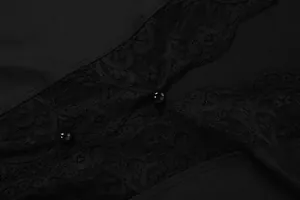 Macro detail of delicate black lace patchwork and buttons on a women's vest top