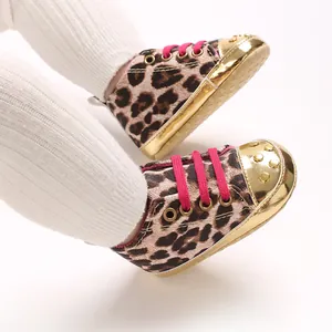 Close-up of leopard print baby shoes with pink laces and gold studded toes.