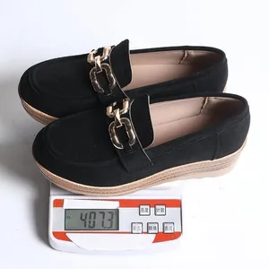 Detaillierte Gewichtsmessung eines schwarzen Wildleder-Loafers mit Goldkette