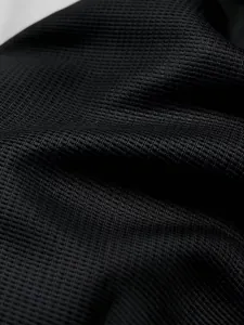 Nahaufnahme des hochwertigen schwarzen Waffelstrickstoffs für atmungsaktive Sport-Shirts