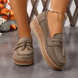 Nahaufnahme von modischen Damen-Wildleder-Loafers mit Quastendetail an den Füßen