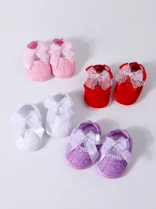 Detailed view of soft-sole baby walking shoes with decorative lace and bows in multiple colors