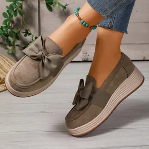 Nahaufnahme von Damen-Plateau-Loafers in Taupe mit schicker Schleife auf Holzboden