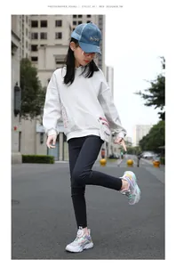 Vista de cuerpo entero de una niña con zapatillas coloridas de moda en una calle urbana.