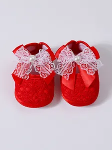 Red soft sole baby shoes with large white lace bow and pearl detail for girls
