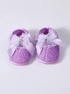 Close-up view of purple baby walking shoes featuring delicate lace patterns and a bow