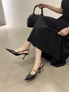 Close-up of black pointed-toe slingback pumps with a metallic gold strap
