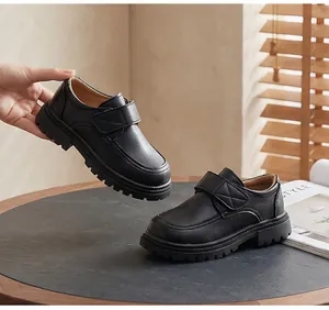 Detail view of boys black school shoes with hook and loop strap on a wooden table