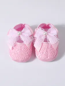 Detailed view of pink baby pre-walker shoes featuring an elegant lace bow and pearl