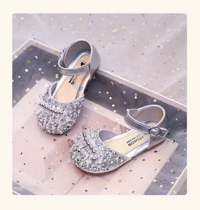 Gros plan de chaussures de princesse argentées étincelantes pour filles avec strass.