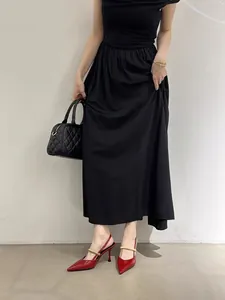 Detail view of red pointed-toe high heels with gold strap and elegant black dress.