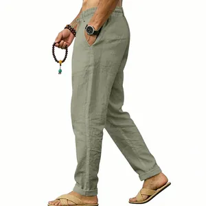 Detailed side view of men's loose linen trousers in sage green with drawstring waist