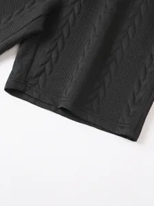 Macro detail shot of black jacquard knit shorts hem showing textured cable pattern